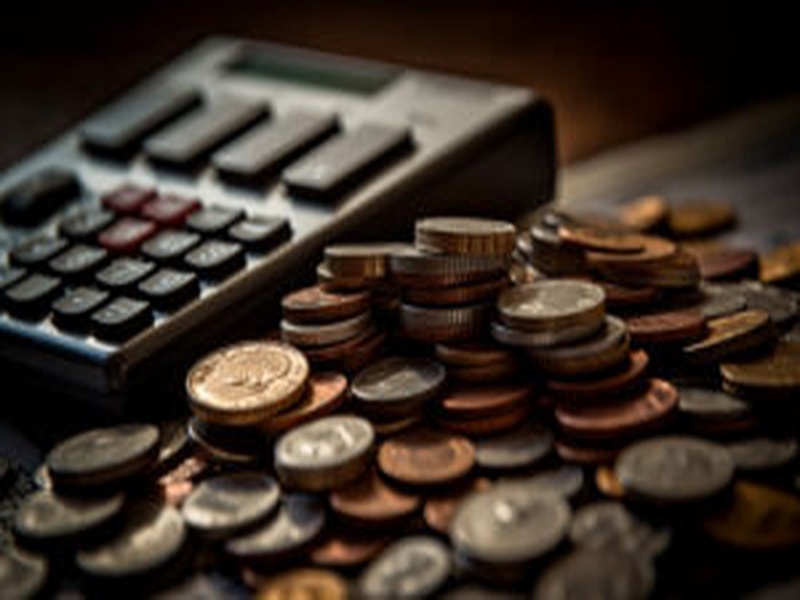 Calculadora ao lado de moedas simbolizando cálculos tributários e planejamento fiscal