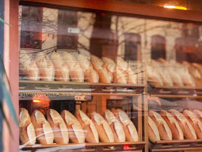 Reforma Tributária para pequenas padarias em destaque através de uma vitrine com pães franceses organizados.